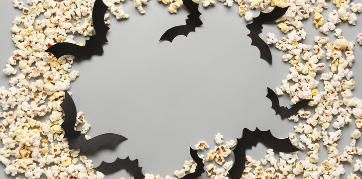 Halloween popcorn and bat decorations forming a spooky border on a gray background with copy space, this arrangement provides ample copy space for seasonal messages or event promotions