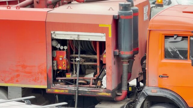 A large orange utility truck stands with an open equipment compartment outdoors. This industrial scene evokes a rugged and powerful feeling of heavy work.