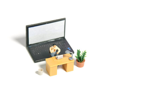 Miniature tiny people toy figure photography. Office worker illustration concept. Top view, a businessman make a phone call with laptop notebook behind