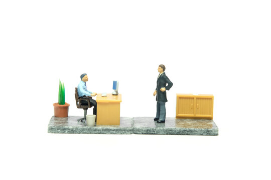 Miniature tiny people toy figure photography. Office complaint illustration concept. A businessman gives a warning to staff employee at office room