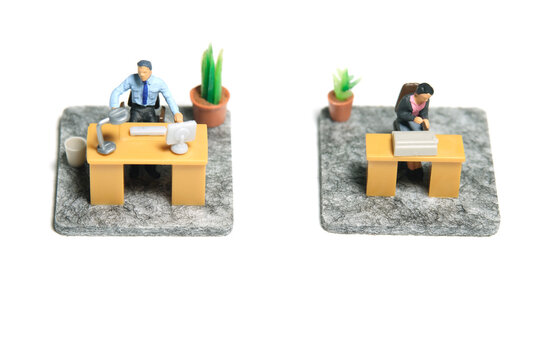 Miniature tiny people toy figure photography. Workspace station layout design concept. A businessman and businesswoman seat on his desk, working their job. Isolated on a white background