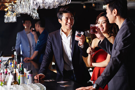 Toast, happy and Asian people at bar with alcohol for social event, celebration and reunion. Party, friends and men with women for conversation, talking and bonding with cheers, drinks and weekend