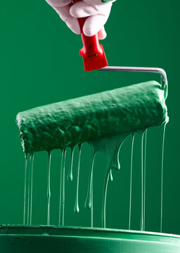 Green Paint Roller with Dripping Paint on Paint Bucket