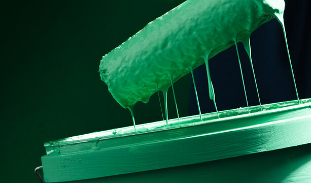 Green Paint Roller with Dripping Paint on Paint Bucket