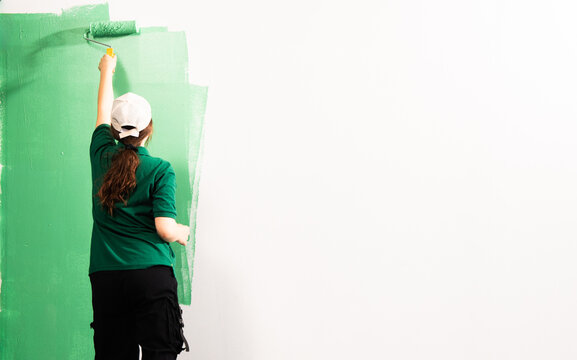 Young women painting a wall with paint roller