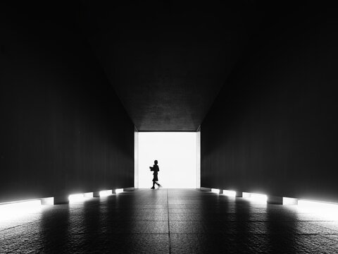 Silhouette people walking toward bright light Exit Black and white minimalist concept