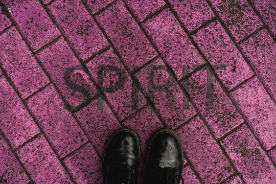 Black shoes on purple pavement with stenciled word 'Spirit'