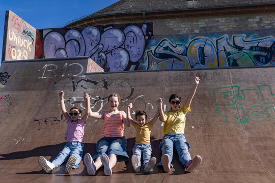 Happy girls sit on a skatepark ramp and cheer together