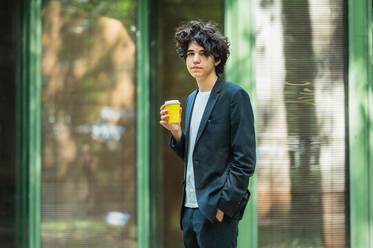 A teenage boy holds a yellow coffee cup during a business break
