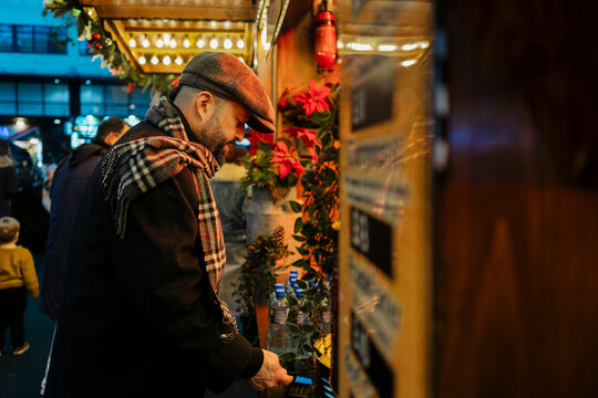Mature man paying at an outdoor Christmas market stall in winter