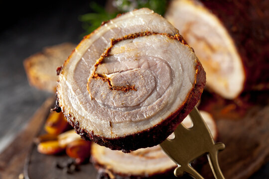 A slice of savory rolled roast pork is held on a vintage fork