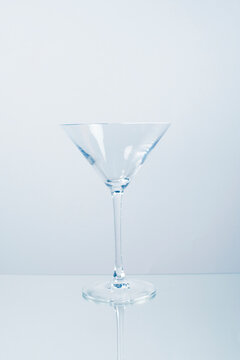 An empty martini glass stands on a reflective mirror surface