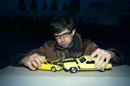Adult playing with yellow toy cars simulating an accident at night