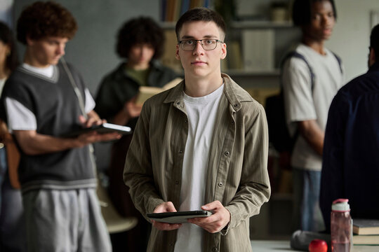 Confident young man holds a tablet in a university classroom