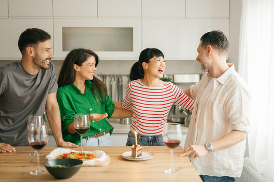 Birthday celebration with friends laughing in bright kitchen