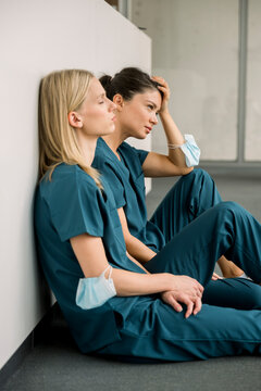 Nurses sitting on hospital floor tired and exhausted from work