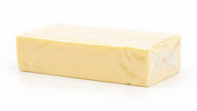 Block of yellow cheese wrapped in clear plastic packaging against transparent background