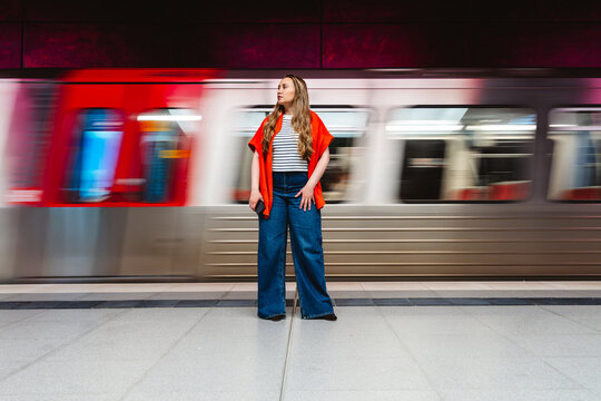 A woman waits at the metro station as a fast train passes by