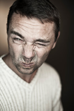 Close up of mature man making funny faces against black background, portrait