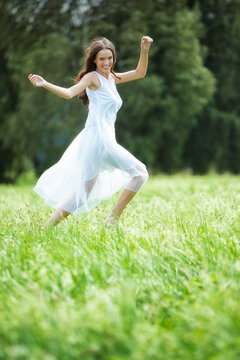 Happy woman wearing white summer dress on a meadow