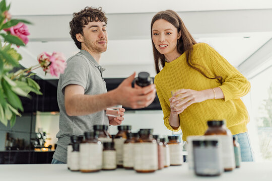 Young man and woman compare health supplements at home
