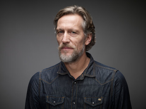 Portrait of pensive mature man in front of grey background