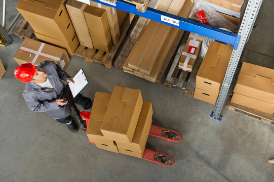 A warehouse worker in Munich, Germany checks inventory using a clipboard in a Bavarian setting