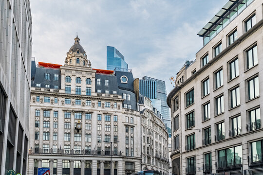 View of the historic architecture of the City of London featuring a prominent clock on the facade and modern skyscrapers in the background, London, England, United Kingdom.