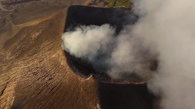 Breathtaking aerial drone footage flying high over the smoking crater of Mount Yasur volcano on Tanna Island, Vanuatu. Active caldera releasing volcanic smoke into the sky above the dramatic landscape