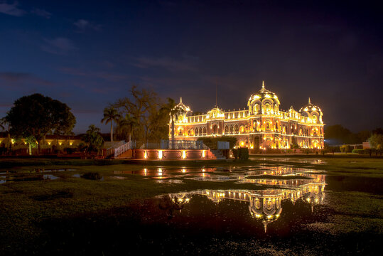 View of Darbar Mahal illuminated at night with its reflection visible in the foreground water, Bahawalpur, Punjab, Pakistan.