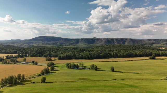 Farmland and hedgerows in evening light below a long flat topped ridge