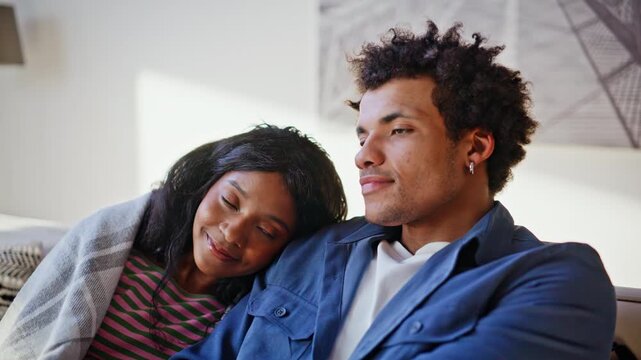 Loving pair connecting hands watching movie television sitting couch closeup