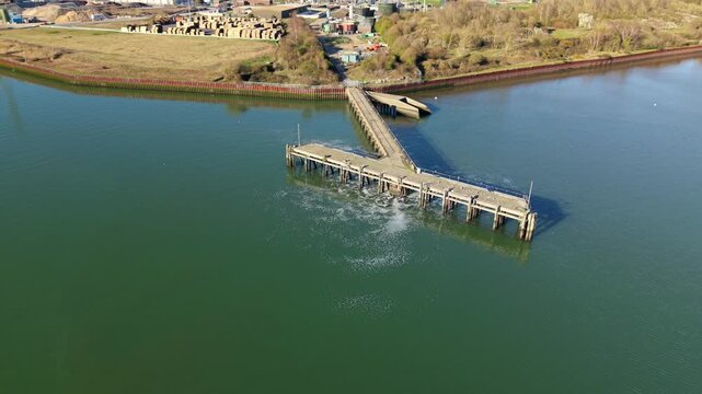 Forward drone flight over a wastewater outfall jetty on the River Orwell with perched sea birds
