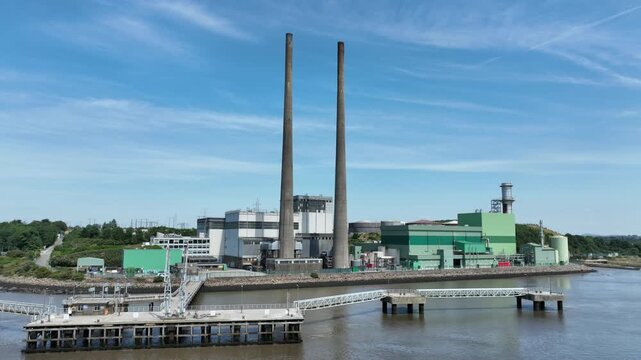 Aerial drone footage of electricity generation facility on the River Suir, County Wexford, Ireland. High-quality energy infrastructure with scenic river landscape,