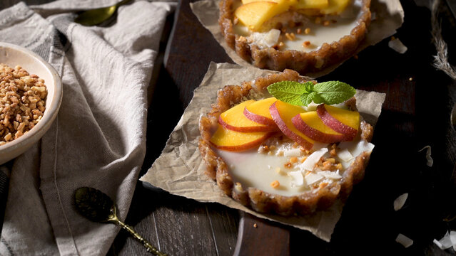 Mini peach tarts with cream filling and coconut flakes on parchment paper