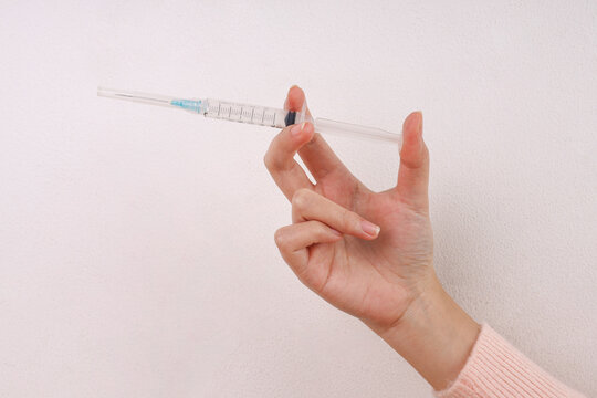 Hand Holding Medical Syringe Between Fingers