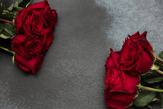 Roses placed on a dark stone surface with no visible hands or people around