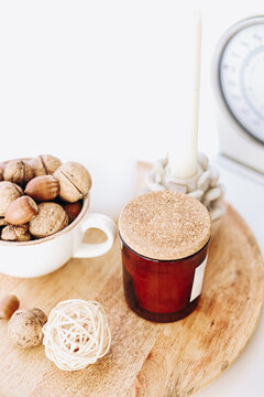 Decorative items on a wooden tray with a candle jar and bowl of nuts in a bright setting
