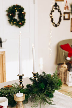 Table setting with Christmas candles greenery and holiday decor in cozy room during winter season