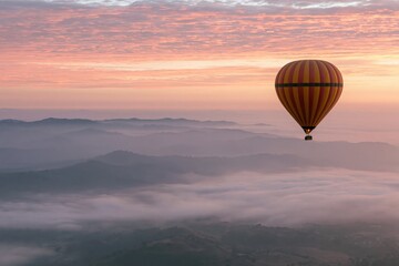 Fototapeta premium The Hot Air Balloon Floating Above Misty Valleys at Sunrise