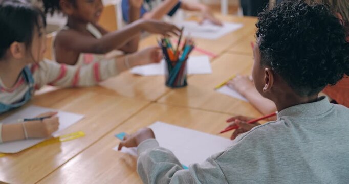 Diverse elementary school students drawing and measuring with rulers on paper in classroom.