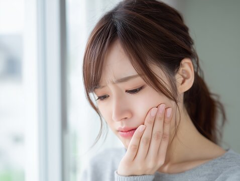歯痛や知覚過敏による頬の痛みで顔をしかめる悩める表情の若い女性のポートレート