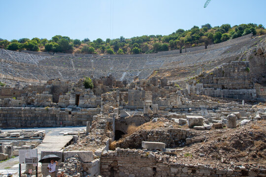 View of the ancient stone ruins of the Great Theatre at Ephesus Ancient City with tiered seating and historic masonry under a clear blue sky in Selcuk, Izmir, Turkey.