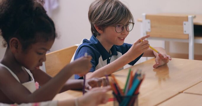 Description: Cute schoolboy with glasses talking and expressing ideas in elementary classroom with classmate.