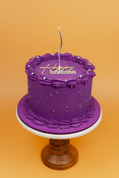 Purple birthday cake with candle and frosting decoration