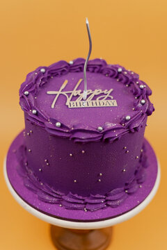 Purple birthday cake celebrating with candle and decorations