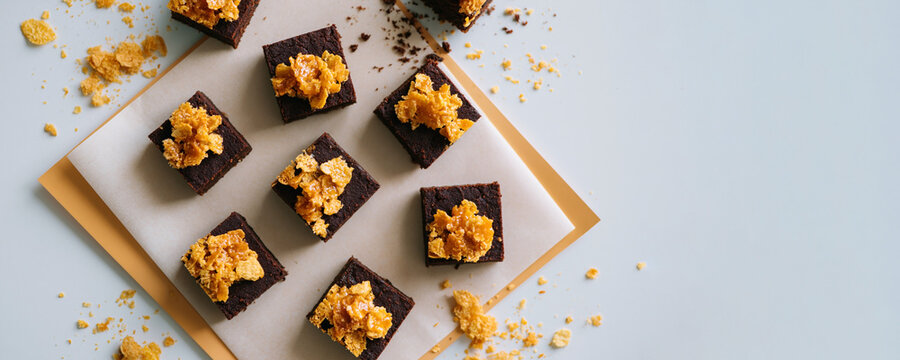 Chocolate brownie bites topped with crunchy cornflakes on paper with copy space