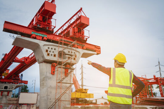 Asian foreman is writing a work summary on a tablet, digitizing the information before leaving work on a construction site for a new concrete road and bridge a critical infrastructure project.