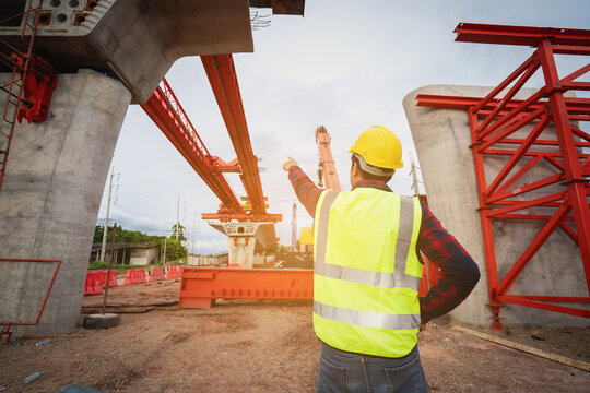 Asian foreman is writing a work summary on a tablet, digitizing the information before leaving work on a construction site for a new concrete road and bridge a critical infrastructure project.
