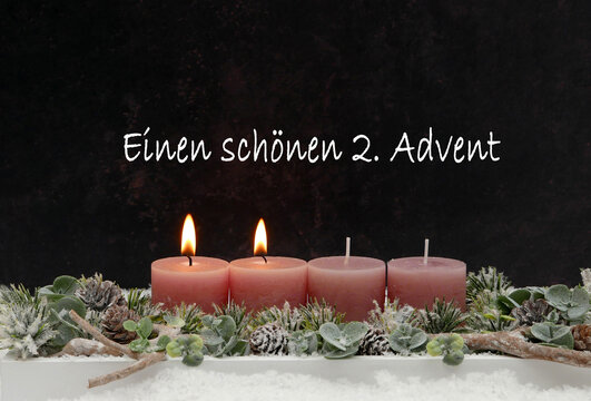 Einen sch&ouml;nen 2. Advent &ndash; Grusskarte mit zwei brennenden altrosa Kerzen auf modernem Adventsgesteck vor dunklem Hintergrund.